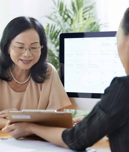 Senior Asian woman talking to insurance agent in office